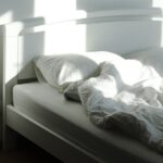 The sleep chart everyone copies has a footnote nobody reads An empty bed and floor lamp in morning sunlight