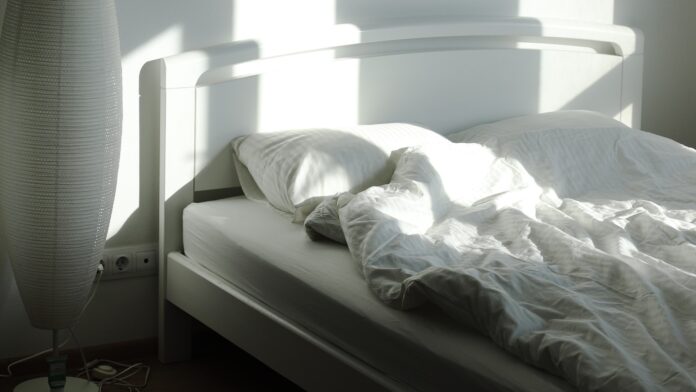 bed-wide An empty bed and floor lamp in morning sunlight