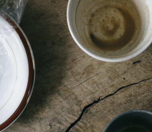 Breakfast is not the most important meal of the day Used breakfast dishes and a crumpled napkin on a wooden table