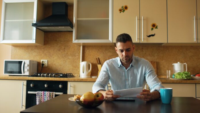 kitchen-wide A man reading a document at a kitchen table
