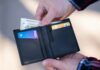 FICO Has a Page Called "Myth Busting." Almost Nobody Has Read It. A black leather bifold wallet held open in a person's hand