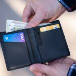 FICO Has a Page Called "Myth Busting." Almost Nobody Has Read It. A black leather bifold wallet held open in a person's hand