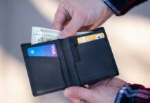FICO Has a Page Called "Myth Busting." Almost Nobody Has Read It. A black leather bifold wallet held open in a person's hand