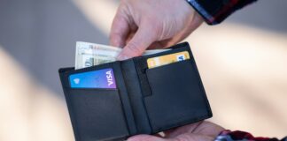 FICO Has a Page Called "Myth Busting." Almost Nobody Has Read It. A black leather bifold wallet held open in a person's hand