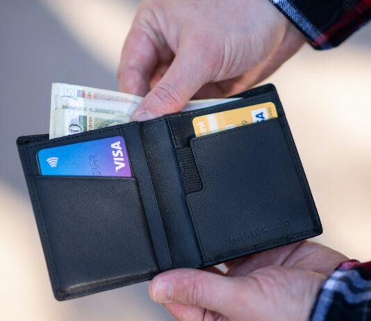 FICO Has a Page Called "Myth Busting." Almost Nobody Has Read It. A black leather bifold wallet held open in a person's hand
