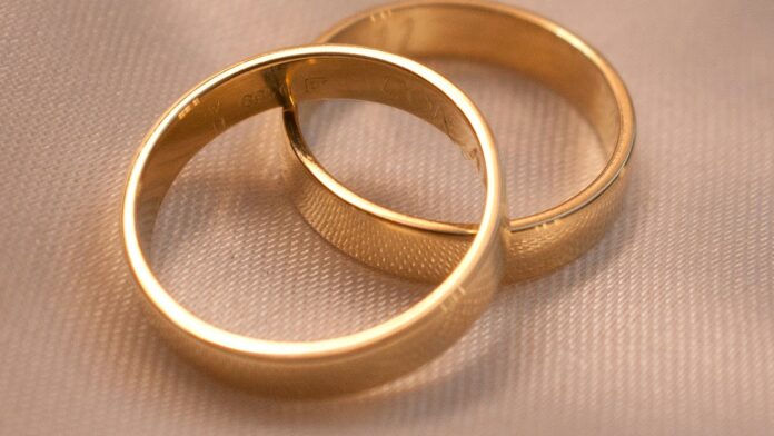 wedding-bands Two interlocking gold wedding bands on a textured surface